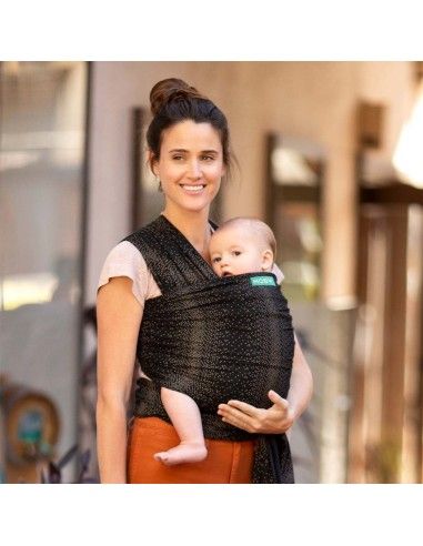 Madre porteando a bebé pequeño con fular elástico de algodón Moby Fleck