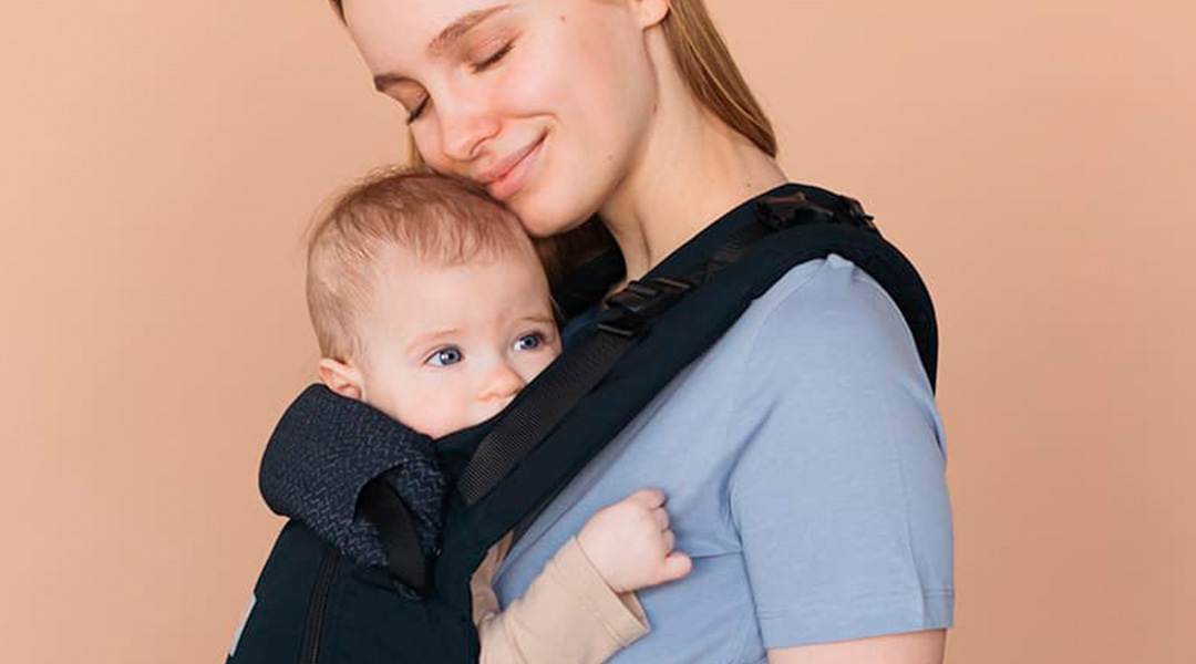 Madre porteando a su bebé con la mochila portabebés Air X de Love & Carry